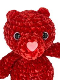 a red crocheted teddy bear on a black background