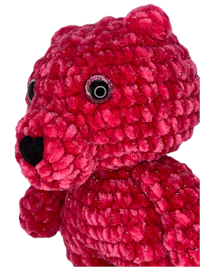 a red crocheted teddy bear is shown against a black background