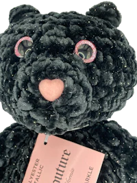 a black teddy bear with a pink tag on it