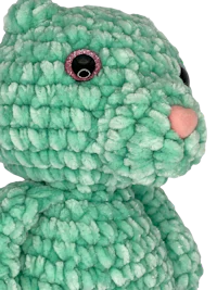a green crocheted teddy bear with pink eyes