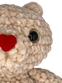 a crocheted teddy bear with a red nose