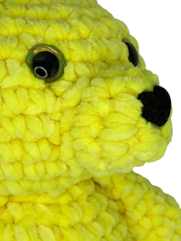 a yellow crocheted teddy bear on a black background