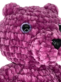 a purple teddy bear is shown against a black background