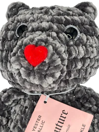 a gray teddy bear with a red heart tag
