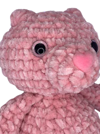 a pink crocheted teddy bear on a black background