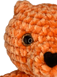 a crocheted orange teddy bear on a black background
